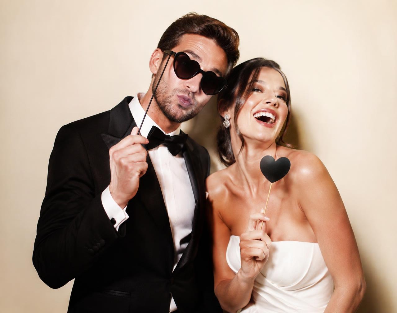 A couple laughing together in a photo booth with props